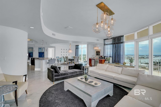 living room featuring wine cooler, an inviting chandelier, and a raised ceiling