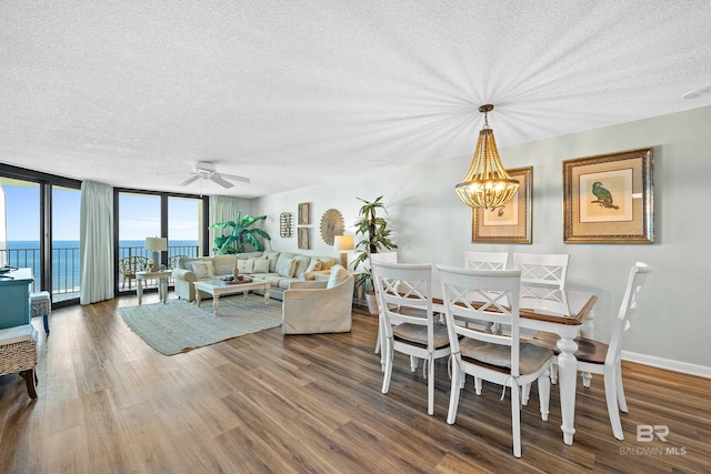 26802 Perdido Beach Blvd Unit 1008, Orange Beach, AL 36561 - dining area featuring a textured ceiling, wood finished floors, a chandelier, a ceiling fan, and a wall of windows