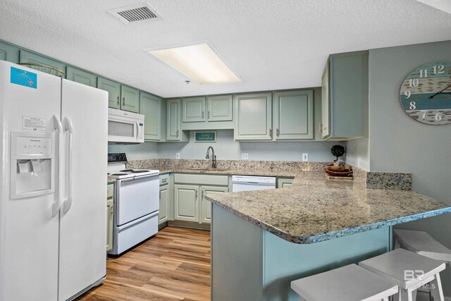 26802 Perdido Beach Blvd Unit 1008, Orange Beach, AL 36561 - kitchen with white appliances, a peninsula, green cabinetry, light wood-style floors, and a textured ceiling