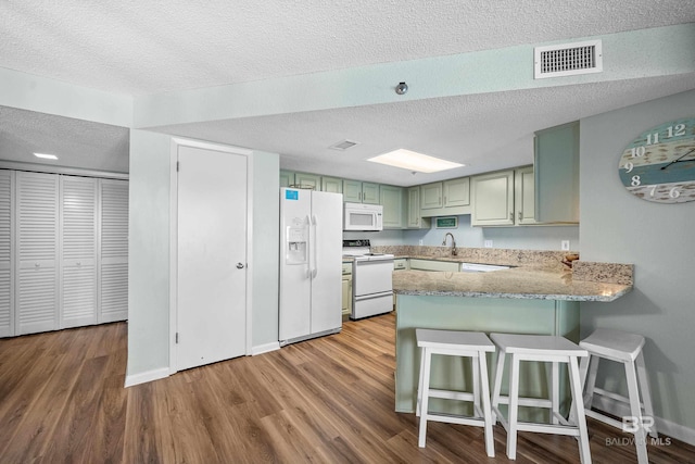 26802 Perdido Beach Blvd Unit 1008, Orange Beach, AL 36561 - kitchen featuring white appliances, a textured ceiling, a peninsula, green cabinetry, and wood finished floors