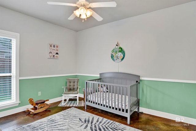 bedroom with ceiling fan, multiple windows, and a nursery area