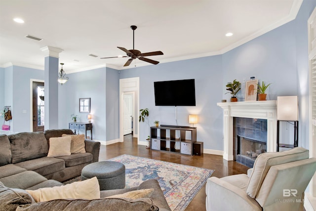 living room with crown molding, a fireplace, ceiling fan, and dark wood-type flooring