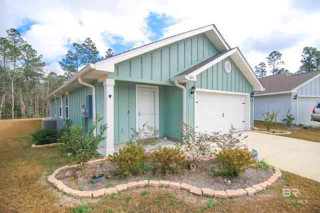 view of front of house with central AC, a garage, and a front lawn