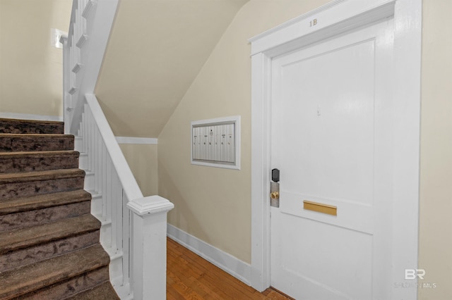 stairway with mail boxes, lofted ceiling, and hardwood / wood-style flooring