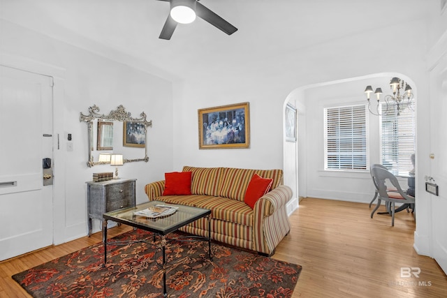 living room featuring ceiling fan with notable chandelier and light hardwood / wood-style floors