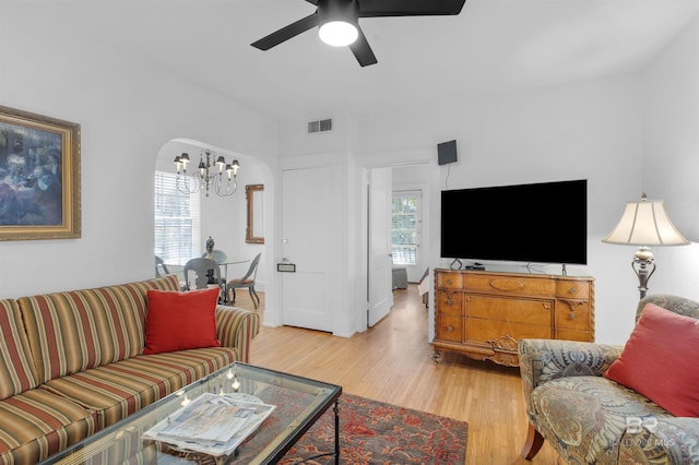 living room with wood-type flooring and ceiling fan with notable chandelier