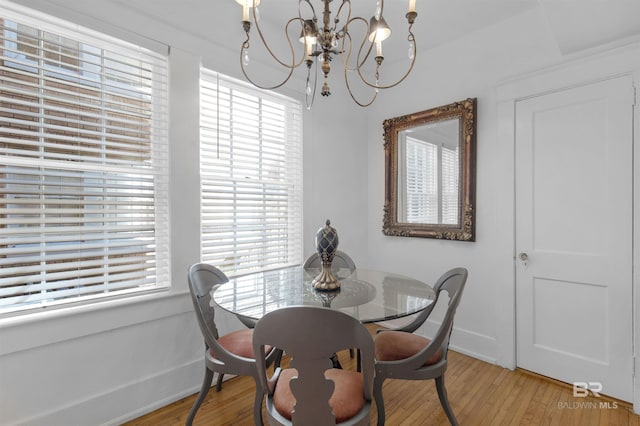 dining space with wood-type flooring and an inviting chandelier