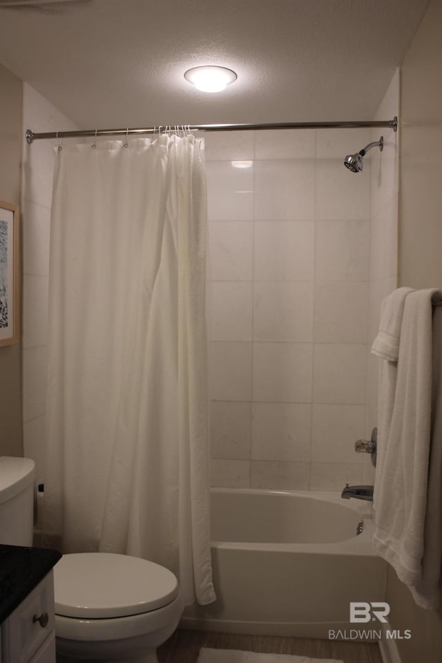 full bathroom featuring shower / bath combo with shower curtain, vanity, toilet, and a textured ceiling