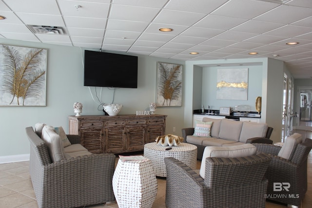 living room featuring tile floors and a paneled ceiling