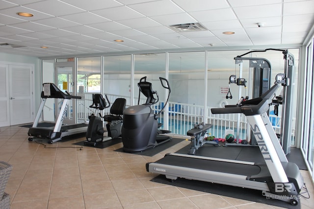 gym featuring a paneled ceiling and light tile floors