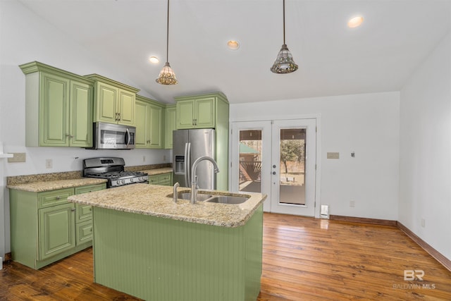 kitchen featuring appliances with stainless steel finishes, decorative light fixtures, a sink, and an island with sink