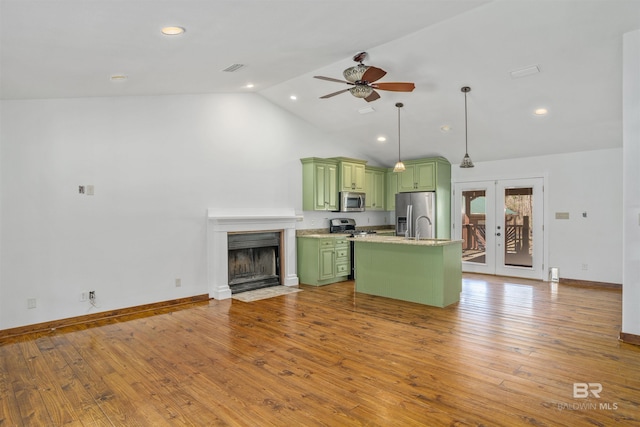 kitchen with pendant lighting, french doors, green cabinets, appliances with stainless steel finishes, and an island with sink