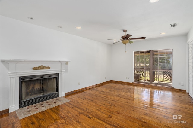 unfurnished living room with a fireplace, wood finished floors, visible vents, and baseboards