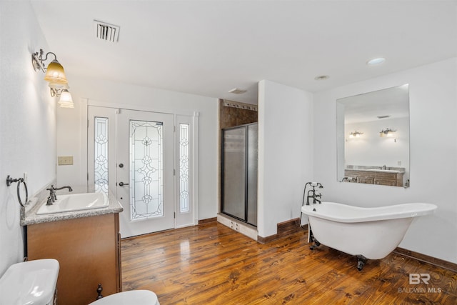 bathroom featuring a freestanding tub, wood finished floors, visible vents, vanity, and baseboards
