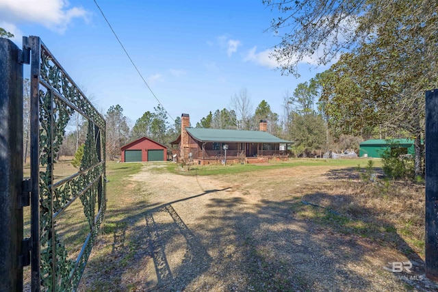 view of yard with dirt driveway, an outbuilding, and a detached garage