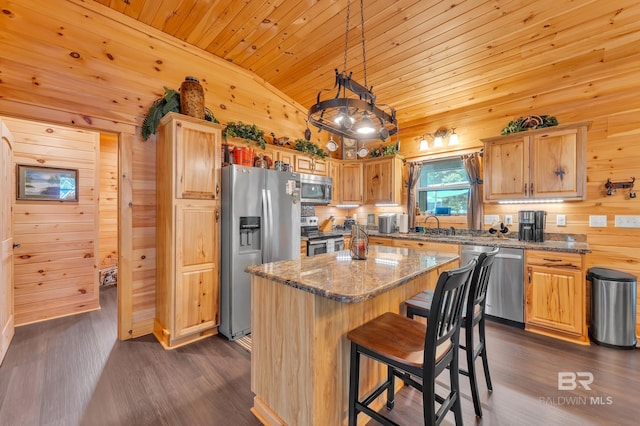30857 Cypress St, Perdido Beach, AL 36530 - kitchen featuring appliances with stainless steel finishes, lofted ceiling, wood walls, dark wood-type flooring, and a kitchen island