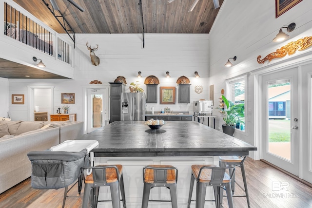 30857 Cypress St, Perdido Beach, AL 36530 - kitchen with stainless steel fridge with ice dispenser, a breakfast bar area, wood finished floors, a high ceiling, and healthy amount of natural light