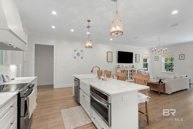 kitchen with visible vents, a kitchen bar, a sink, a notable chandelier, and stainless steel appliances