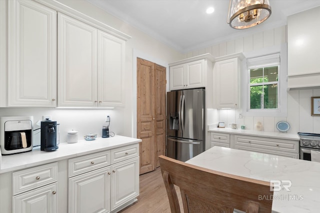 kitchen featuring light wood-style floors, appliances with stainless steel finishes, ornamental molding, and white cabinetry