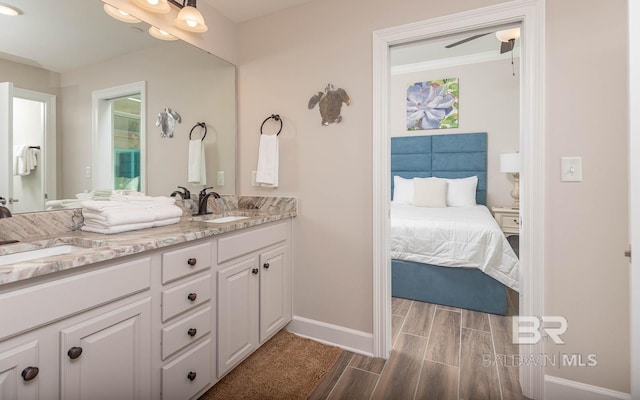 bathroom featuring baseboards, a sink, double vanity, and wood tiled floor