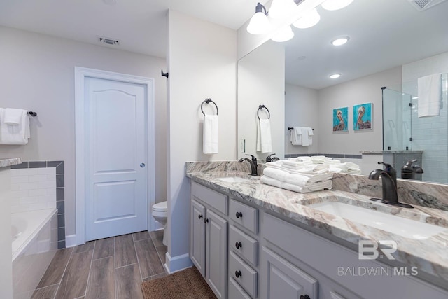 bathroom with a sink, a shower stall, toilet, and visible vents