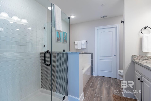 bathroom with a bath, visible vents, wood finish floors, a shower stall, and vanity