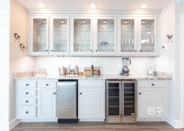 bar featuring wine cooler, indoor wet bar, wood tiled floor, a sink, and backsplash