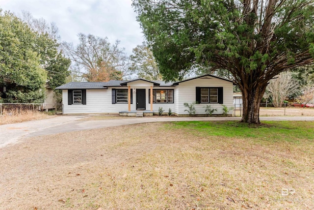 ranch-style house featuring a front yard, fence, and driveway