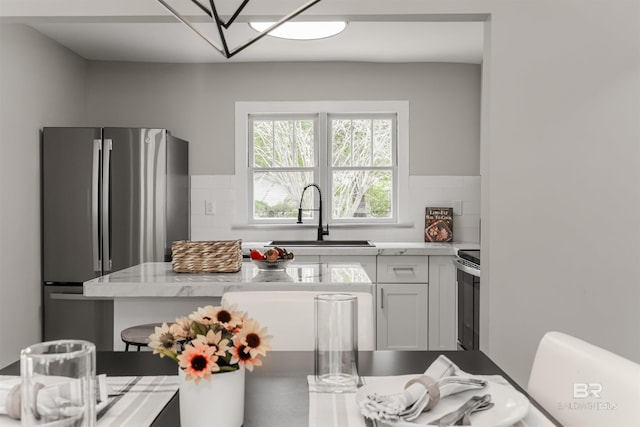 kitchen featuring sink, tasteful backsplash, stainless steel refrigerator, range with electric cooktop, and white cabinets