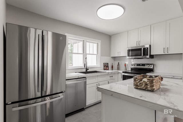 kitchen featuring sink, stainless steel appliances, white cabinets, and light stone countertops