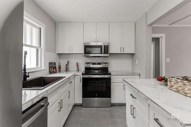 kitchen with sink, light tile patterned flooring, white cabinets, and appliances with stainless steel finishes