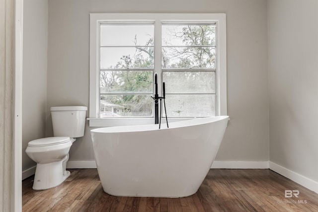 bathroom with hardwood / wood-style floors, plenty of natural light, and a bath