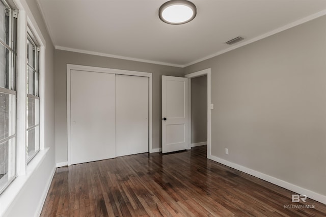 unfurnished bedroom with dark hardwood / wood-style flooring, ornamental molding, and a closet