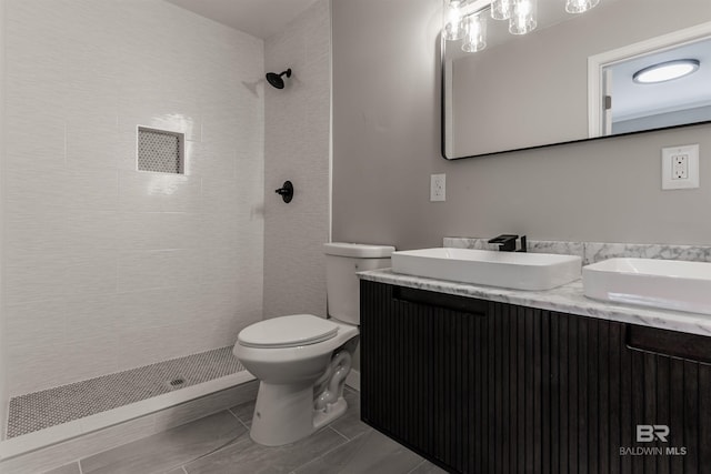 bathroom with vanity, toilet, and tiled shower