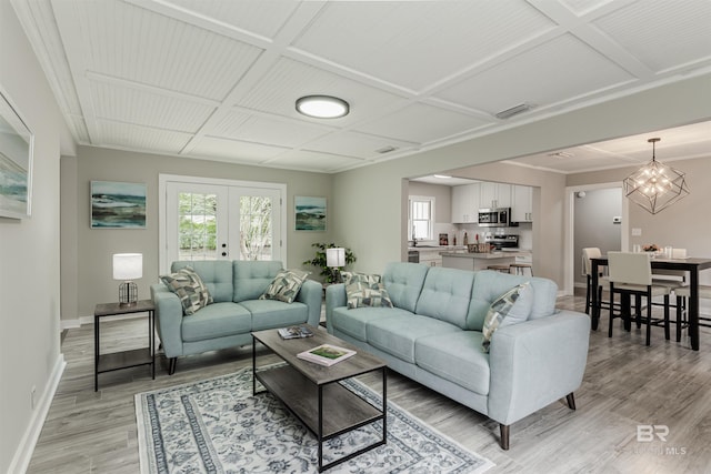 living room featuring coffered ceiling, plenty of natural light, light hardwood / wood-style floors, and french doors