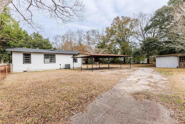 exterior space with central AC, a carport, and a storage unit