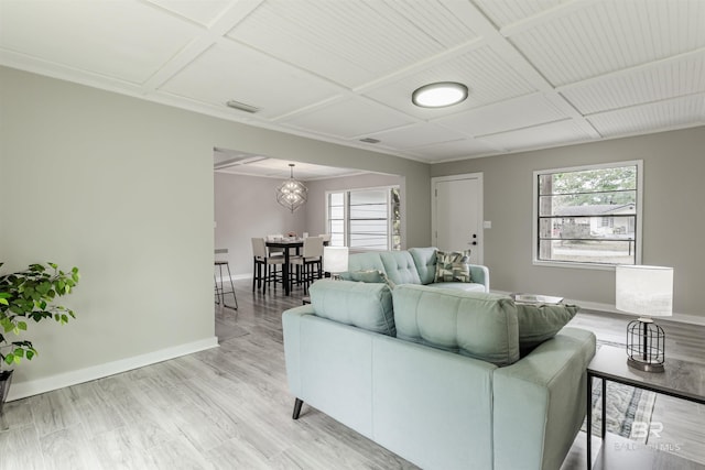 living room featuring plenty of natural light, coffered ceiling, and light hardwood / wood-style flooring