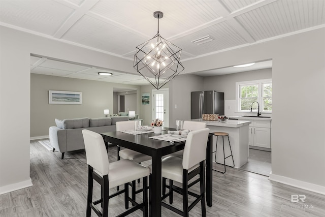 dining area with a chandelier, sink, and light wood-type flooring