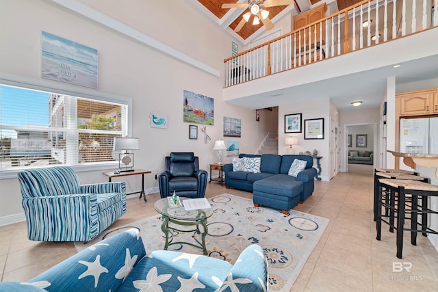 living room with baseboards, ceiling fan, stairway, a high ceiling, and light tile patterned flooring