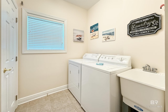 laundry area with light tile patterned floors, a sink, washer and dryer, laundry area, and baseboards