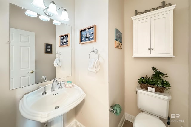 bathroom featuring a sink, toilet, and an inviting chandelier