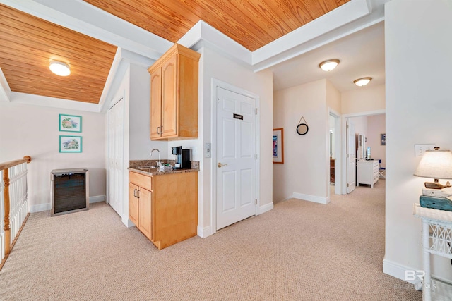 kitchen featuring a tray ceiling, light colored carpet, light brown cabinetry, wooden ceiling, and baseboards