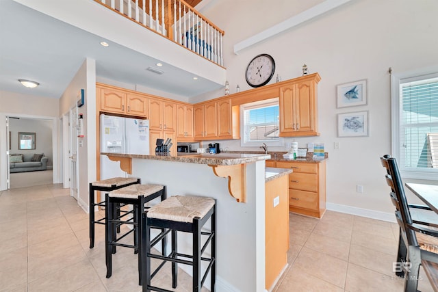 kitchen featuring a healthy amount of sunlight, light tile patterned flooring, a breakfast bar area, and light brown cabinetry