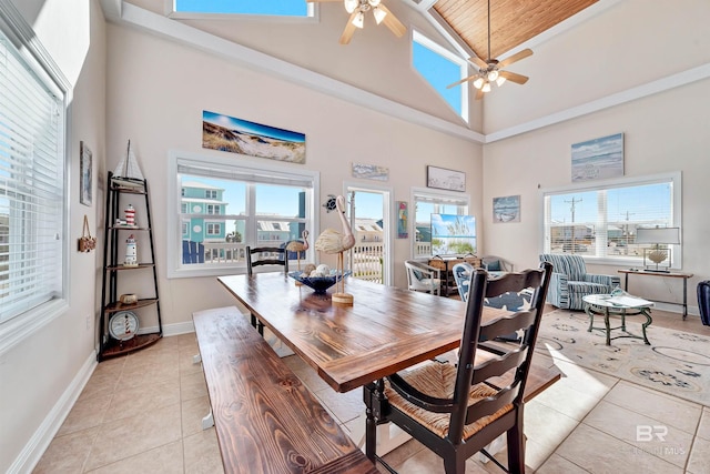 dining space with light tile patterned floors, high vaulted ceiling, a ceiling fan, and baseboards