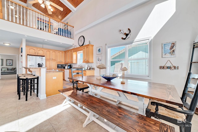 dining space featuring ceiling fan, a high ceiling, and light tile patterned flooring