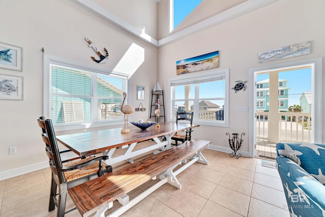 dining space with plenty of natural light, a towering ceiling, baseboards, and light tile patterned floors