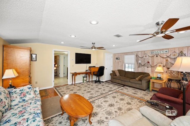 living room with ceiling fan, light wood-type flooring, a textured ceiling, and lofted ceiling