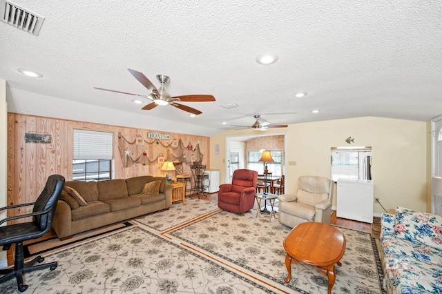 living room with a textured ceiling, light hardwood / wood-style flooring, and ceiling fan