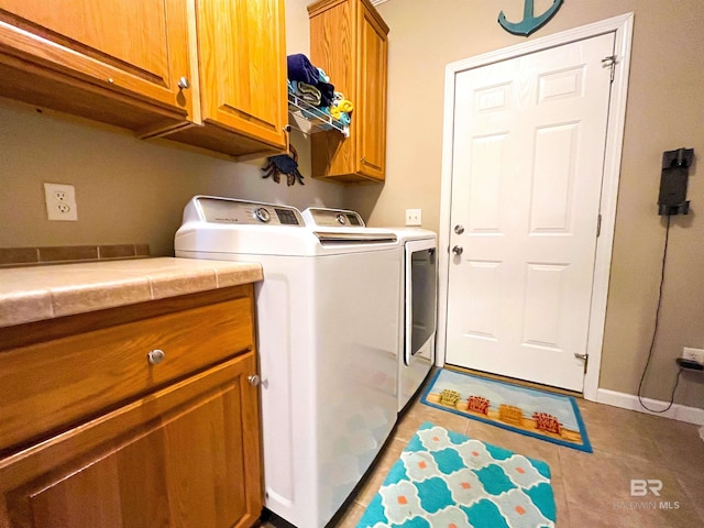 laundry area with tile patterned flooring, cabinets, and washing machine and clothes dryer