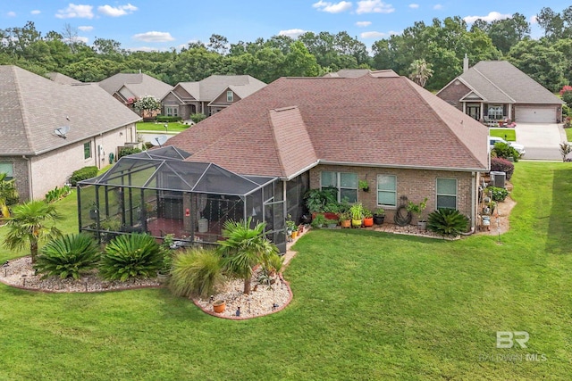 rear view of property featuring a lanai and a lawn